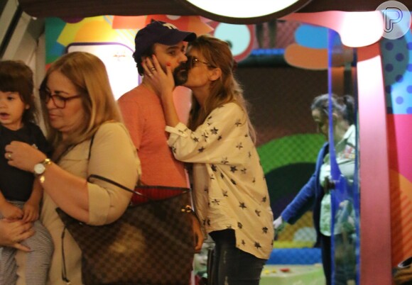 Alinne Moraes beija o marido, Mauro Lima, antes de entrar em área infantil de shopping