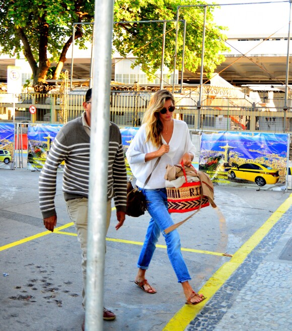Usando peças básicas e rasteirinha, Gisele Bündchen embarcou no aeroporto do Rio carregando uma bolsa de palha estilosa, que deu um toque descolado à produção