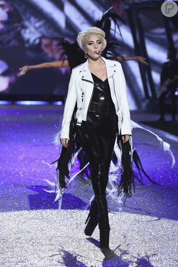 Lady Gaga com macacão Yves Saint Laurent com uma jaqueta branca