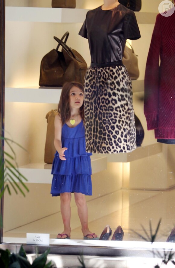 Suri Cruise flagrada em momento de encantamento com roupas de adulto em uma loja feminina