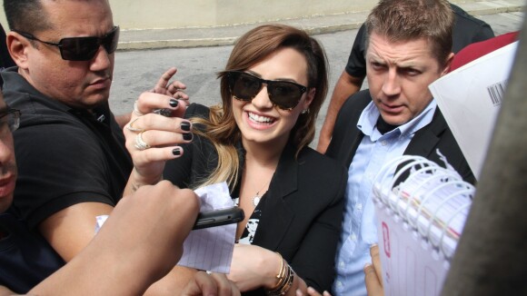 Demi Lovato distribui autógrafos para fãs em porta de hotel no Rio de Janeiro