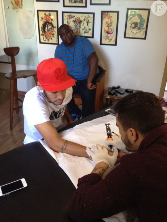 Neymar é observado por um amigo durante o procedimento no estúdio Tattootradition