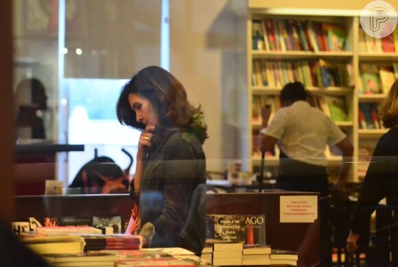 Pensativa, Fátima Bernardes escolhe livros em shopping no Rio
