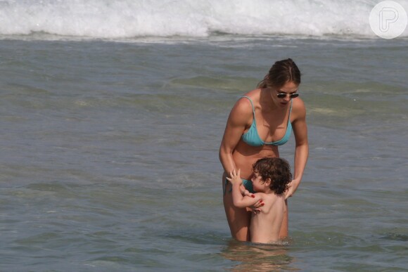 Letícia Birkheuer pega o filho, João Guilherme, no colo após ele demonstrar estar com medo das ondas do mar da praia do Pepê