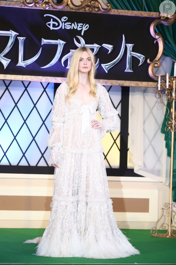 Elle Faning usou um vestido longo branco de renda para promover o filme 'Malévola'