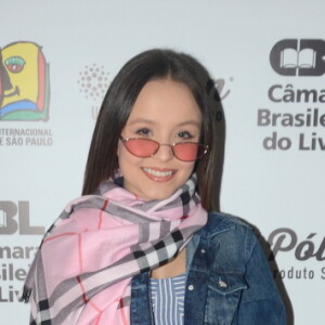 Larissa Manoela elegeu um vestido midi listrado, jaqueta jeans, pashmina rosa com xadrez e tênis