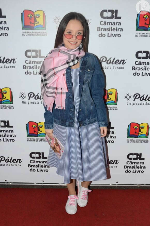 Larissa Manoela elegeu um vestido midi listrado, jaqueta jeans, pashmina rosa com xadrez e tênis
