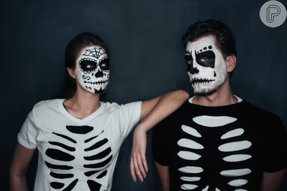A fantasia de caveira para o Halloween pode ser feita com sobreposição de blusas preta e branca rasgadas e uma maquiagem artística