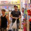 Rafael Cardoso deixa loja de brinquedos com a filha, Aurora, e sacola de compras