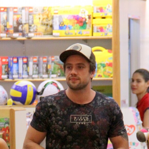 Rafael Cardoso deixa loja de brinquedos com a filha, Aurora, e sacola de compras