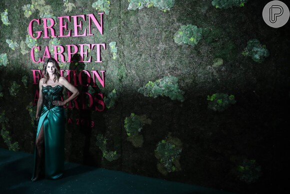 O vestido verde-esmeralda de Cindy Crawford, assinado por Versace foi feito a partir de seda orgânica. O decote strapless (tomara-que-caia) foi comporto por cristais Swarovski sem chumbo