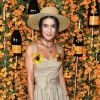 Detalhe floral: a blogueira brasileira Camila Coelho escolheu um vestido longo e liso com duas flores amarelas fixadas na alça do vestido