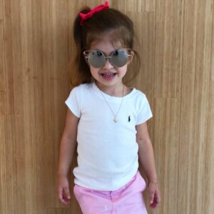 Valentina, filha de Mirella Santos e Ceará, usou t-shirt branca, saia rosa e óculos de sol estiloso