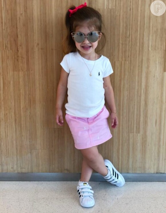 Valentina, filha de Mirella Santos e Ceará, usou t-shirt branca, saia rosa e óculos de sol estiloso