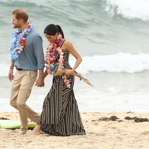 Meghan Markle e príncipe Harry tiraram os sapatos para andar pela Bondi Beach