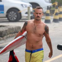 Sem camisa, Paulinho Vilhena exibe corpo em forma e surfa em praia carioca