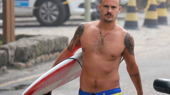 Sem camisa, Paulinho Vilhena exibe corpo em forma e surfa em praia carioca