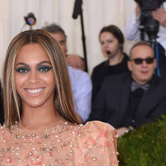 Beyoncé com os cabelos lisos e risca central, o cabelo bem simples combina com o look cheio de informação