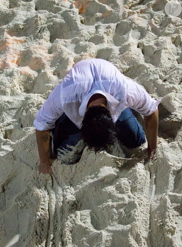 Enrico (Joaquim Lopes) perde as forças e começa a se deixar cair na areia, em cena de 'Império'