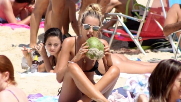 Yasmin Brunet se refresca com água de coco em dia de praia no Rio de Janeiro