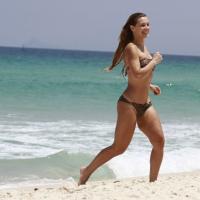 Carolina Dieckmann, com biquíni comportado de oncinha, curte praia no Rio