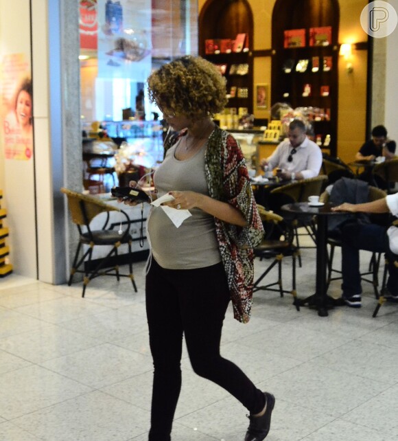 Taís Araújo mexe no celular enquanto caminha no aeroporto