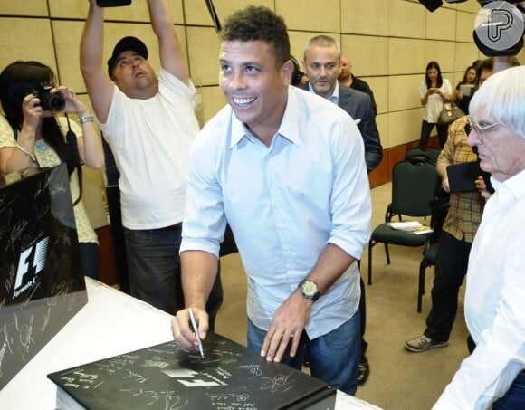 O ex-jogador Ronaldo autografa capa do livro que será leiloado para arrecadar fundos para instituições de caridade em 20 países