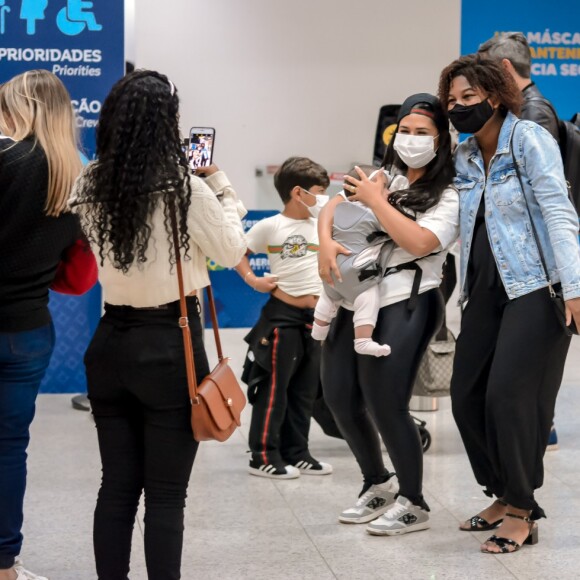 De boné, Simone faz foto com fã antes de viajar com família