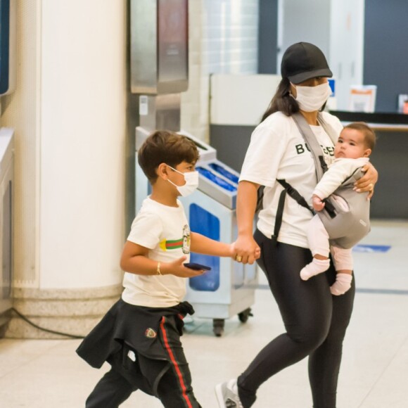 Simone embarca com a filha caçula, Zaya, em canguru e de mãos dadas com Henry