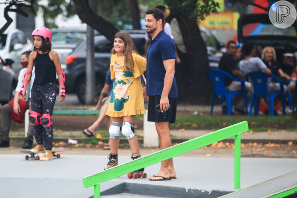 De bermuda e chinelo, Cauã Reymond auxilia a filha em pista de skate no Rio