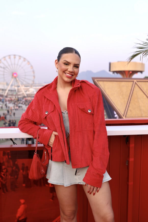 A influenciadora Vivi Wanderley usa conjunto jeans como top e minissaia e jaqueta vermelha