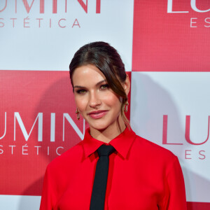 Andressa Suita usou vestido vermelho com cauda, fenda e mangas longas para coquetel de lançamento de filial de sua clínica de estética, Lumini, em SP