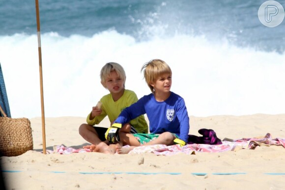 Francisco e João brincam na areia enquanto os pais jogam vôlei