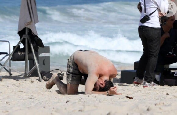 Marcelo Adnet se agacha e coloca a cabeça na areia na praia de Ipanema, RJ