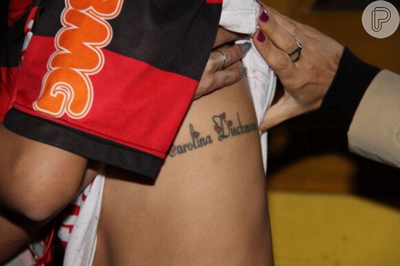 Carolina mostra de perto a tatuagem com seu nome no corpo da fã