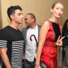 Ao lado do namorado, Joe Jonas, Gigi Hadid usou vestido Tommy Hilfiger de cetim vermelho e sandálias de salto alto preto