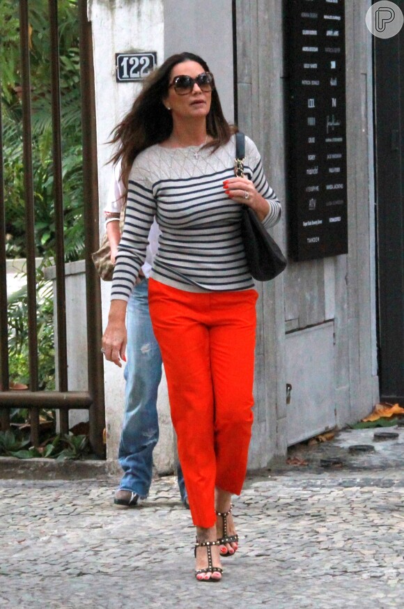 A ex-modelo Luiza Brunet combinou sua blusa listrada em off white e azul com uma calça na cor laranja e sandálias de salto