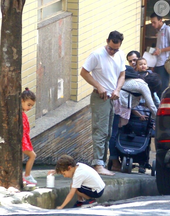 Camila Alves arruma carrinho de bebê do filho enquanto os outro dois brincam na calçada