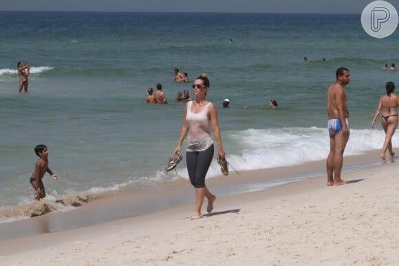 Simpática, Juliana Didone aparece na praia da Barra para correr e tomar banho de mar e acena para fã