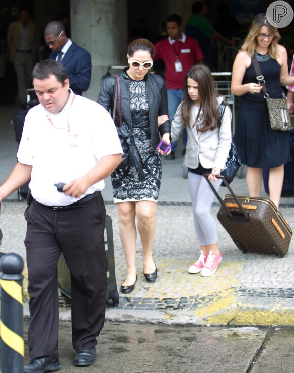 Sophia desembarca no aeroporto do Rio carregando a sua malinha Louis Vuitton ao lado da mãe e exibe um terninho claro no mesmo tom da calça e tênis rosa para dar uma cor ao visual