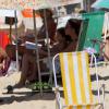 Cláudia Abreu se protege do sol e curte leitura com o filho em praia do Rio de Janeiro