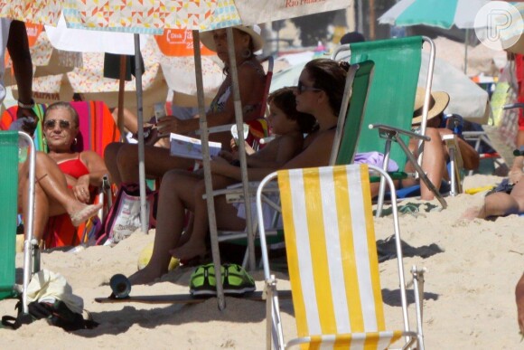 Cláudia Abreu se protege do sol e curte leitura com o filho em praia do Rio de Janeiro