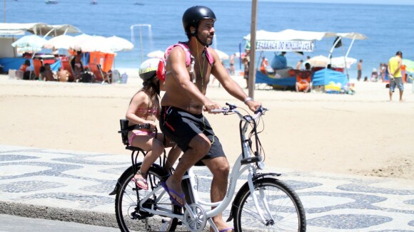 Marcos Palmeira leva a filha na garupa de bicicleta em orla de praia carioca