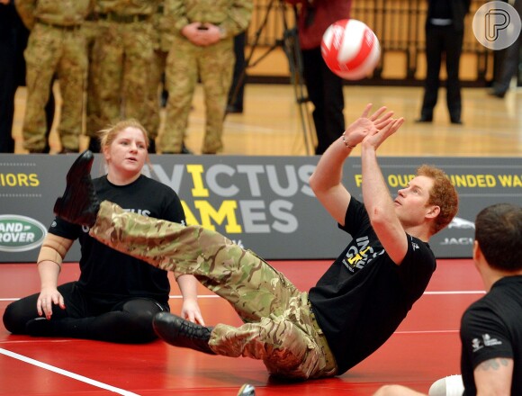 Prince Harry senta no chão para jogar vôlei com ex-militares deficientes físicos, em 7 de março de 2014