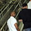 Kanye West esboça um sorriso ao subir a escada rolante