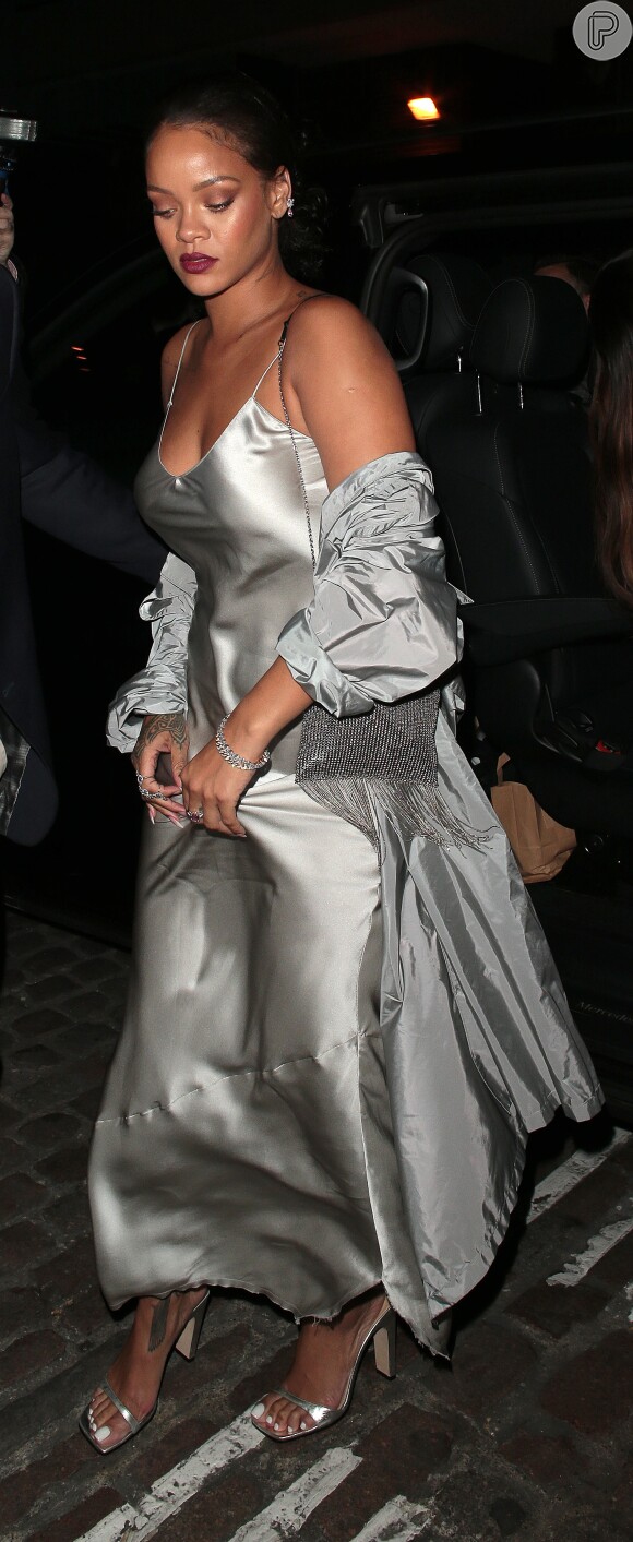A cantora Rihanna apostou em sandálias de salto prateadas para combinar com o vestido longo de seda