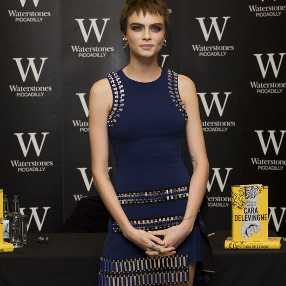 Com os fios castanhos no evento de autógrafos de seu livro, Cara Delevingne exibiu um refinado vestido com detalhes metálicos, complementado por sapatos sem salto