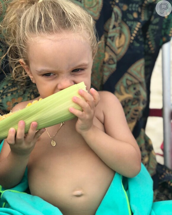 Mariana Bridi mostrou a filha, Aurora, comendo milho verde na praia