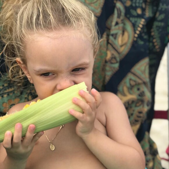 Mariana Bridi mostrou a filha, Aurora, comendo milho verde na praia