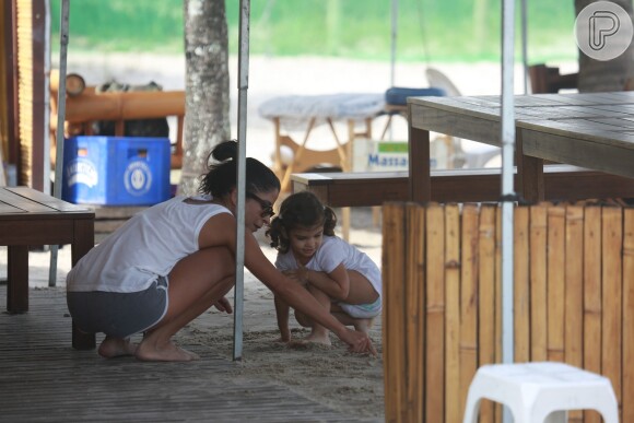 Anna Lima e Sofia conversam e brincam na areia ao lado do quiosque